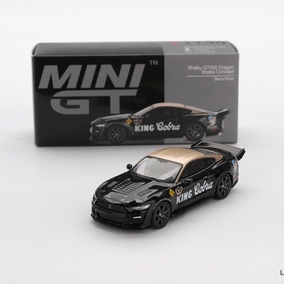 Miniatura de carro de corrida preto com detalhes dourados e texto KING Cobra em branco e caixa preta ao fundo.