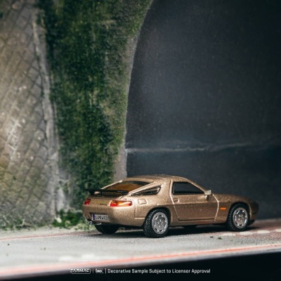 Miniatura de carro desportivo dourado em estrada perto de túnel com musgo