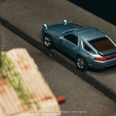 Miniatura de carro desportivo metálico azul estacionado em superfície cinza