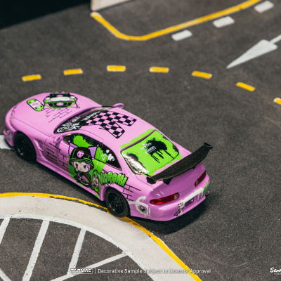 Carro miniatura cor-de-rosa com gráficos verdes, sobre estrada simulada com linhas brancas e amarelas.