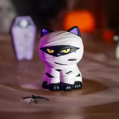 Figurinha de gato mumificado com olhos amarelos e aranha de plástico