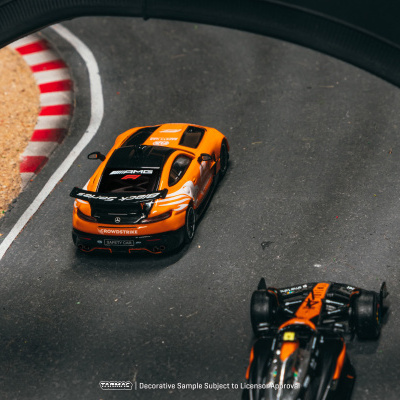 Carro de corrida em miniatura laranja e preto numa pista de corrida
