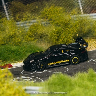 Modelo de carro de corrida preto com detalhes amarelos numa pista de corrida