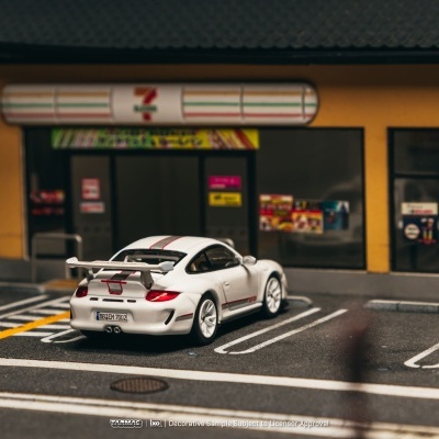 Carro desportivo branco com faixa vermelha estacionado em frente a loja 7-Eleven amarela