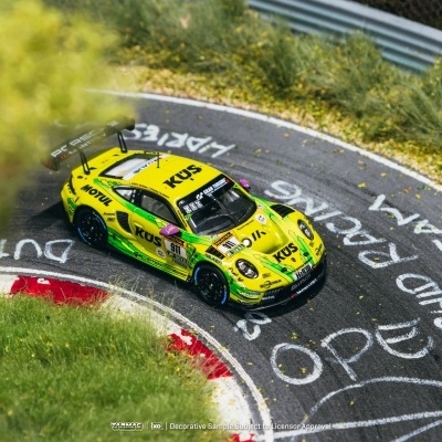 Miniatura de carro de corrida amarelo com detalhes verdes e preto na pista curva com texto branco no asfalto