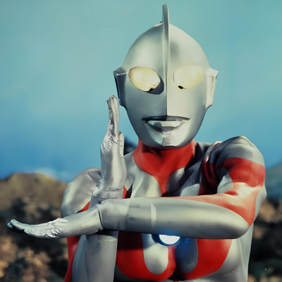 Boneco de Ultraman prateado e vermelho com olhos amarelos em fundo de céu azul