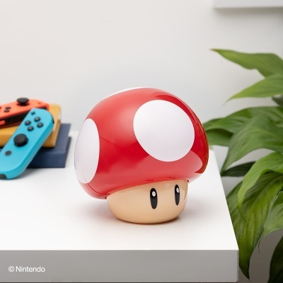 Boneco cogumelo vermelho e branco na mesa com controlos Nintendo Switch ao fundo