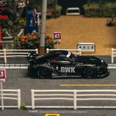 Carro de brinquedo preto com letras brancas numa estrada de miniatura