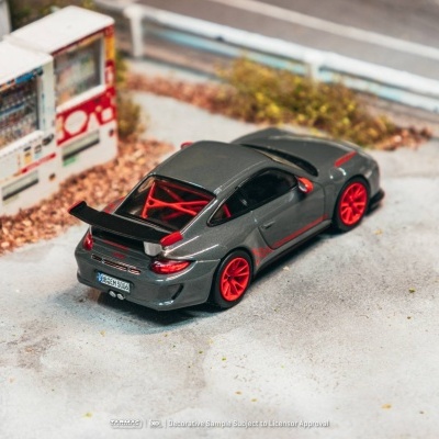 Miniatura de carro desportivo cinza com rodas vermelhas perto de máquina KIRIN