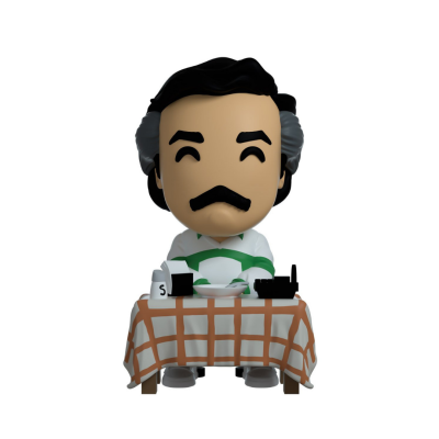 Figura Funko Pop sentado numa mesa com toalha quadriculada e objetos