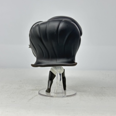 Boneco pequeno com cabelo preto, collants pretos e brancos, base transparente, fundo neutro.