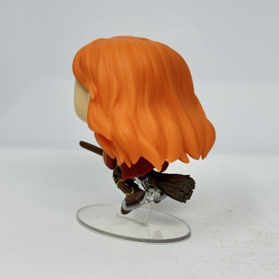 Figura colecionável de vinil com cabelo laranja ondulado montada numa vassoura em base transparente