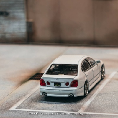 Miniatura de carro branco estacionado em parque de estacionamento urbano