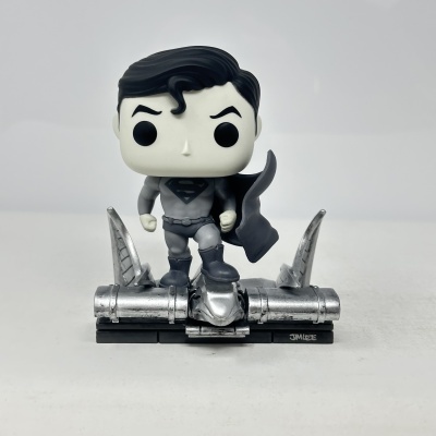 Figura Funko Pop do Superman cinza e preto com base metálica prateada.