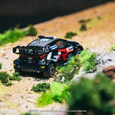 Miniatura de carro de rali preto com detalhes vermelhos numa estrada de terra