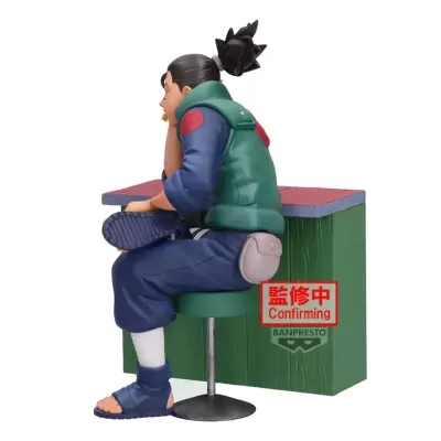 Figura colecionável de personagem sentado num banco verde com colete verde e calças azuis