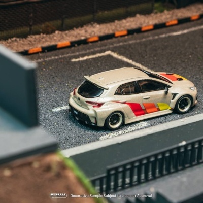 Carro de brinquedo branco com riscas coloridas estacionado em parque de estacionamento em miniatura