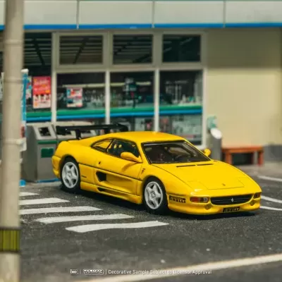 Miniatura de carro desportivo amarelo em cenário urbano com loja FamilyMart ao fundo