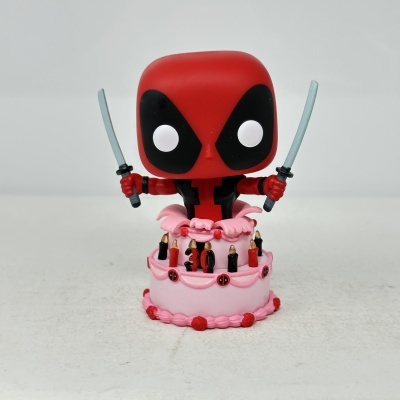 Figurinha Deadpool Funko Pop em cima de bolo rosa com velas e número 30