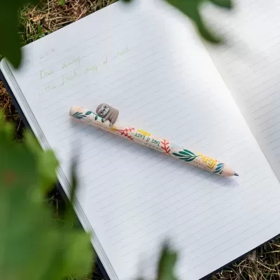 Caderno aberto com escrita e caneta decorada com bicho-preguiça e texto TAKE IT EASY.