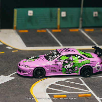 Miniatura de carro desportivo rosa com padrões gráficos verdes num parque de estacionamento.
