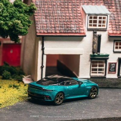 Miniatura de carro de colecionador verde metálico com teto preto em cenário com casa e árvore.