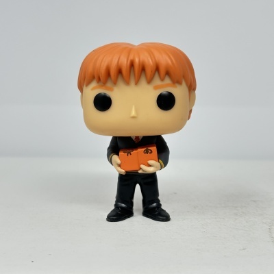 Figura Funko Pop personagem ruivo de fato preto segurando caixa laranja