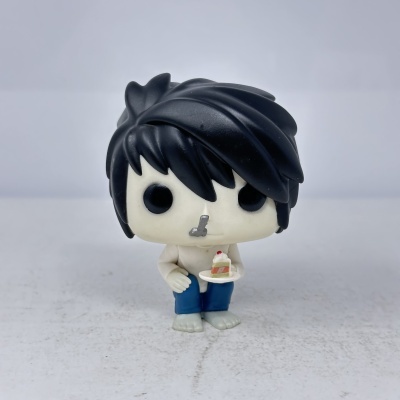 Figura colecionável em vinil com cabelo preto e despenteado segurando bolo