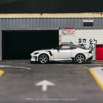 Miniatura de carro desportivo branco com detalhes em preto junto a garagem cinzenta com sinais asiáticos