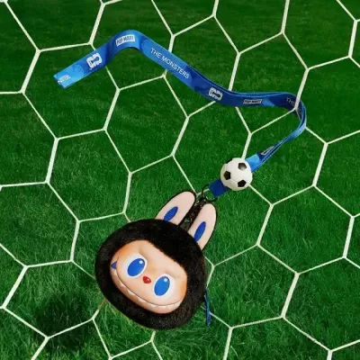 Chaveiro com personagem de orelhas de coelho e fita azul com texto sobre rede de baliza e relvado