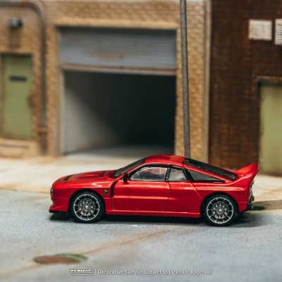 Miniatura de carro desportivo vermelho metálico com jantes prateadas numa rua urbana