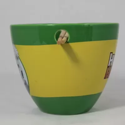 Copo verde com faixa amarela sobre fundo cinzento