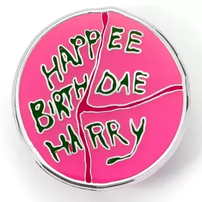 Broche redondo rosa com texto verde 'HAPPEE BIRTHDAE HARRY'