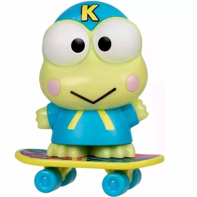 Boneco de sapo verde de brinquedo com roupa azul e letra K, em cima de skate amarelo com rodas azuis.