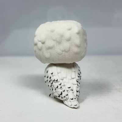 Figura de coruja branca aveludada com detalhes pretos.