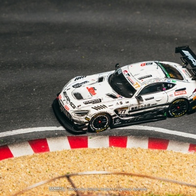 Carro de corrida miniatura branco com marcas AMG, TARMAC e MOTUL na pista de corrida