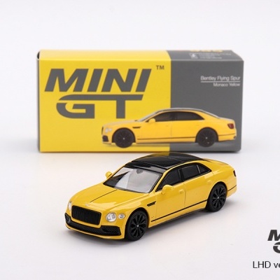 Miniatura de Bentley Flying Spur amarelo e preto e embalagem Mini GT ao fundo