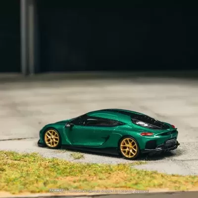 Miniatura de carro desportivo verde com jantes douradas em cenário de estrada e relva