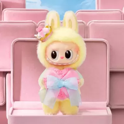 Boneco de peluche amarelo com orelhas de coelho e coroa numa cadeira cor-de-rosa