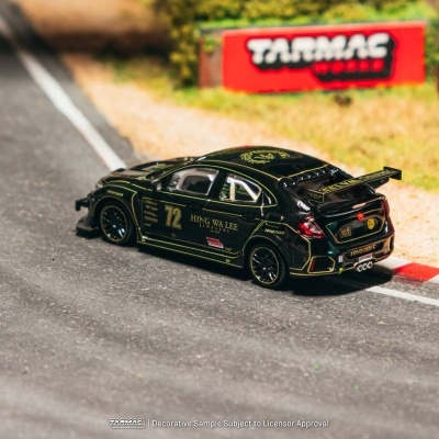 Miniatura de carro de corrida preto com detalhes amarelos e número 72 numa pista com pneus e sinal vermelho.