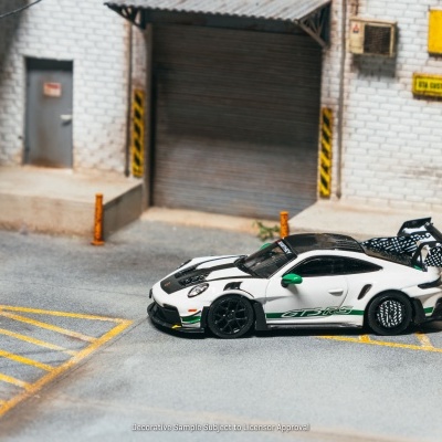 Carro de corrida branco com detalhes preto e verde estacionado em área com pintura amarela no chão