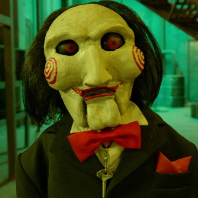 Boneco com máscara de rosto pálido e laço vermelho