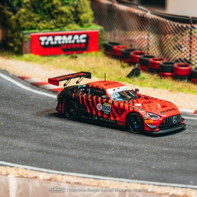 Miniatura de carro de corrida vermelho e preto com texto TARMAC WORKS ao fundo