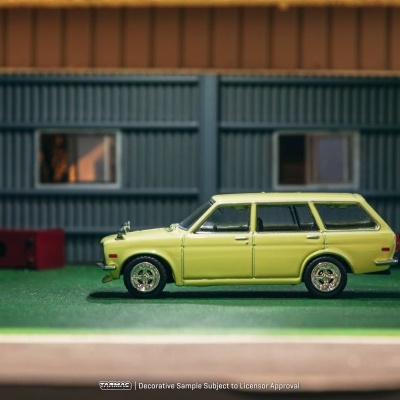 Miniatura de carro amarelo com jantes cromadas num cenário com relvado e paredes azuis