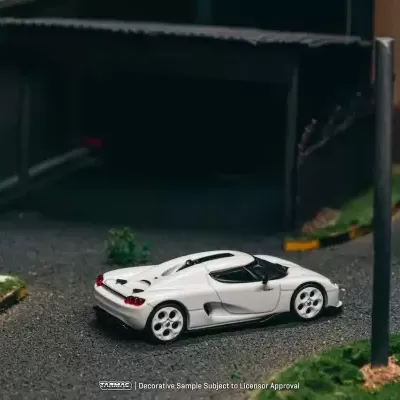 Miniatura de carro desportivo branco em modelo de estrada com postes e relva