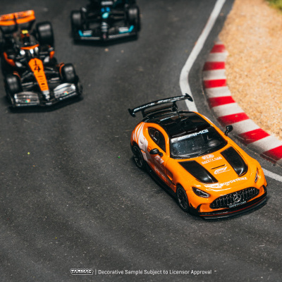Carrinhos de brinquedo de corridas numa pista com um carro de segurança laranja e preto e dois carros de corrida.