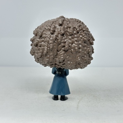 Figura pequena de brinquedo com casaco azul e cabelo castanho encaracolado vista de costas