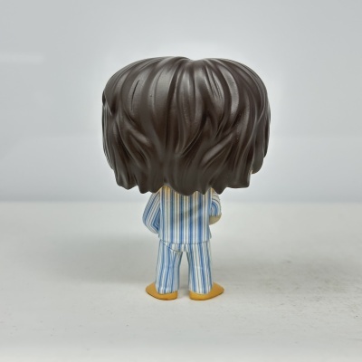 Figura de vinil com cabelo castanho e pijama às riscas azuis e brancas vista por trás