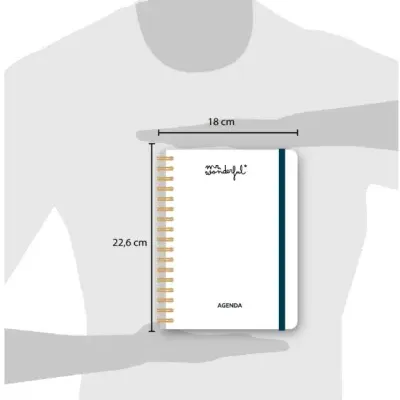 Agenda branca com espiral dourada, elástico azul e texto na capa mostrando as medidas.
