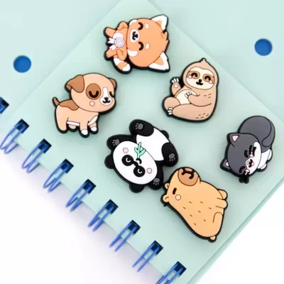 Seis pins de animais coloridos sobre um caderno azul claro